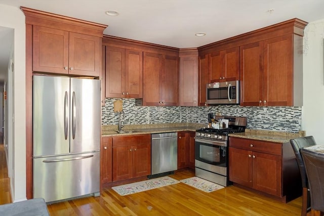 106 Walnut St Unit 4, Somerville, MA 02145 - kitchen with stainless steel appliances, light wood-style floors, a sink, light stone countertops, and backsplash