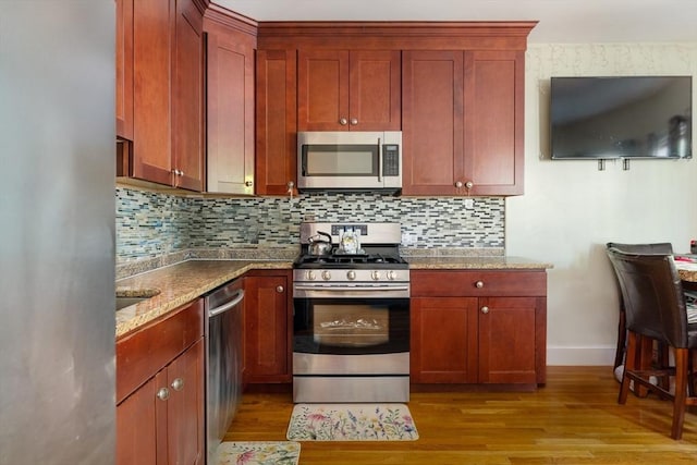 106 Walnut St Unit 4, Somerville, MA 02145 - kitchen featuring stainless steel appliances, baseboards, light wood finished floors, and stone countertops
