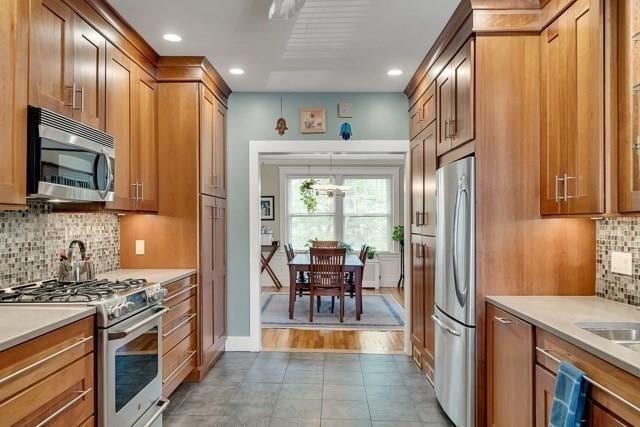 15 Thatcher St Unit F2-2, Brookline, MA 02446 - kitchen with stainless steel appliances, brown cabinetry, decorative backsplash, light countertops, and recessed lighting
