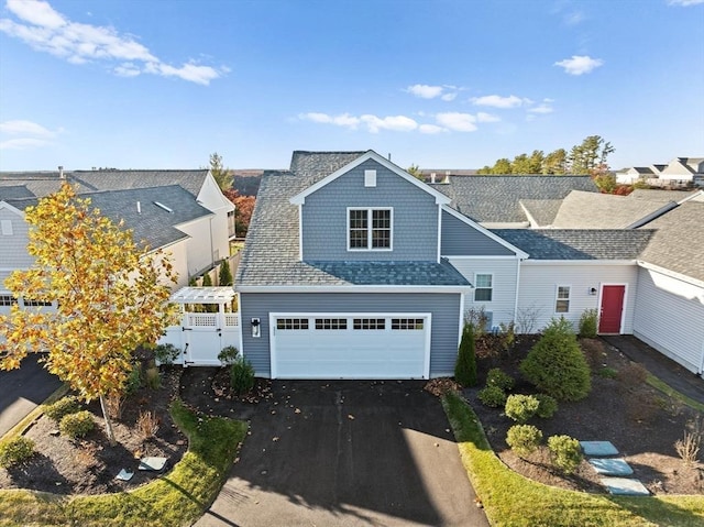 view of front of property with aphalt driveway, roof with shingles, and a garage