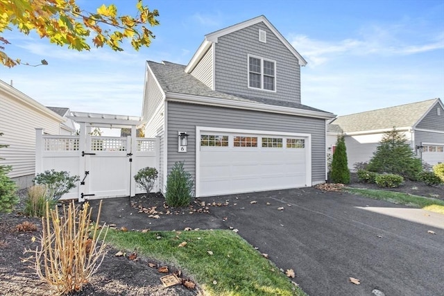 view of front of property featuring a garage, a gate, and aphalt driveway