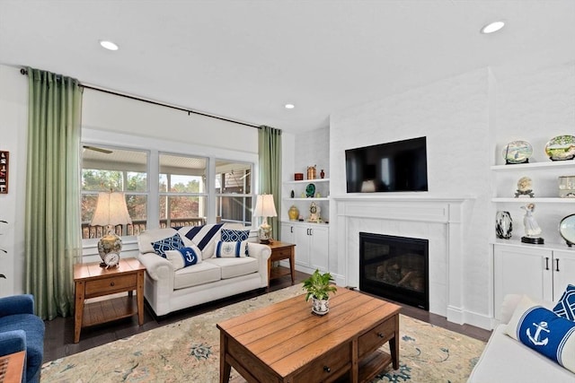 living area featuring built in shelves, a tiled fireplace, and wood finished floors