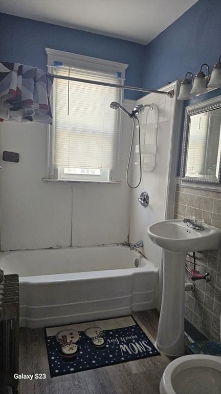 bathroom featuring toilet, tub / shower combination, tile walls, and wood finished floors