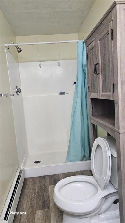 full bath with a baseboard heating unit, curtained shower, toilet, and wood finished floors