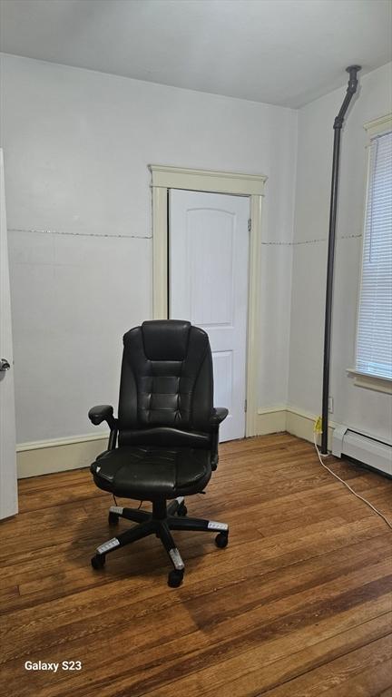 living area featuring a baseboard heating unit and wood finished floors