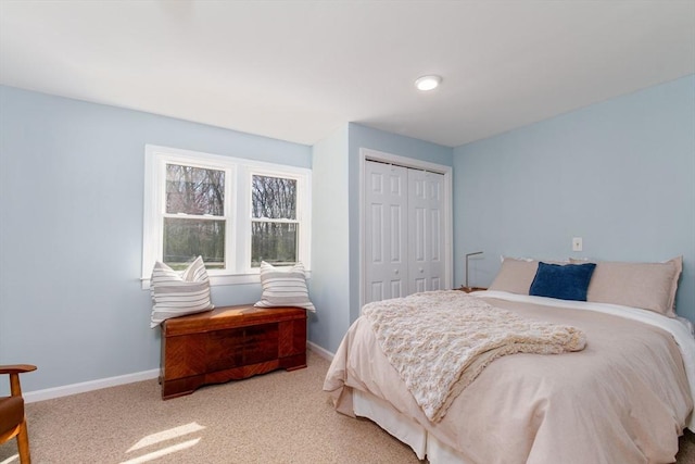 carpeted bedroom with a closet and baseboards