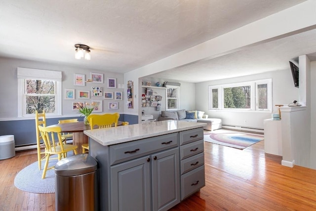 kitchen with baseboard heating, open floor plan, plenty of natural light, and gray cabinets