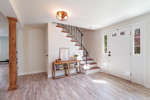 foyer featuring stairs, baseboards, decorative columns, and wood finished floors