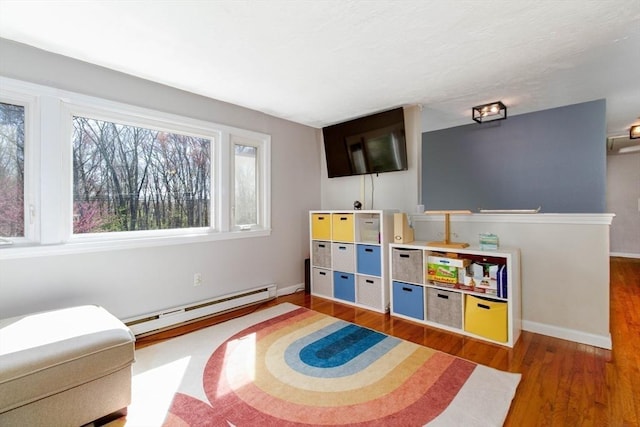 rec room featuring baseboards, a baseboard radiator, and wood finished floors