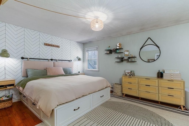 bedroom featuring an accent wall and wood finished floors