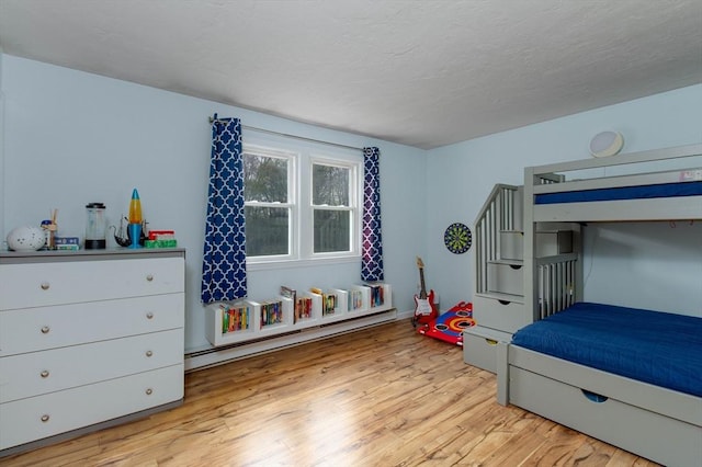 bedroom featuring a textured ceiling, a baseboard radiator, and light wood-type flooring