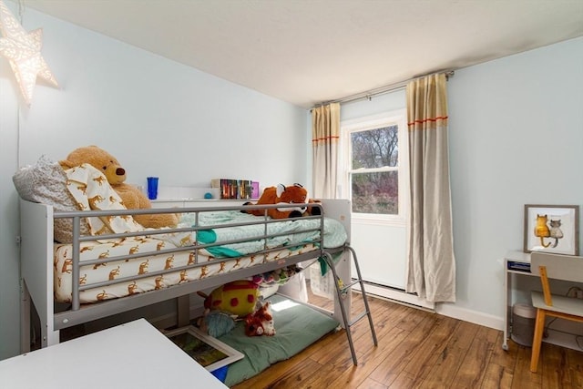 bedroom with baseboards, baseboard heating, and hardwood / wood-style flooring