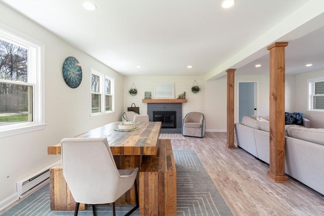 dining space featuring ornate columns, a baseboard radiator, a glass covered fireplace, and recessed lighting