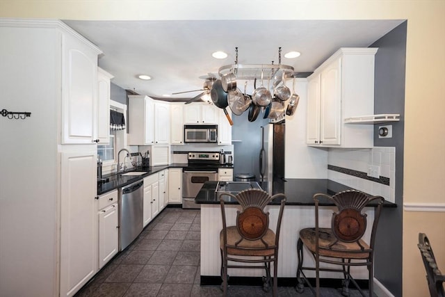 249 E Squantum St Unit 2, Quincy, MA 02171 - kitchen with stainless steel appliances, a peninsula, dark countertops, white cabinets, and recessed lighting