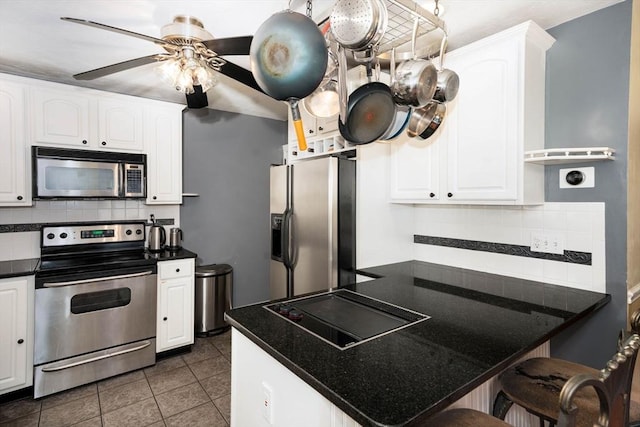 249 E Squantum St Unit 2, Quincy, MA 02171 - kitchen featuring appliances with stainless steel finishes, decorative backsplash, dark countertops, white cabinetry, and a breakfast bar