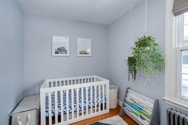 249 E Squantum St Unit 2, Quincy, MA 02171 - bedroom with radiator, a crib, and wood finished floors