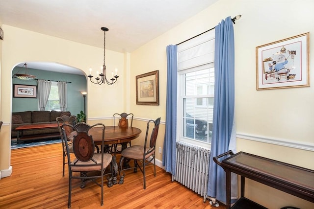 249 E Squantum St Unit 2, Quincy, MA 02171 - dining room with radiator heating unit, wood finished floors, arched walkways, and a chandelier