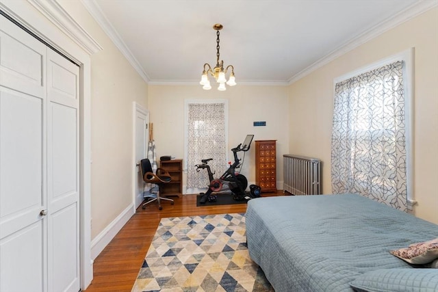 bedroom with baseboards, radiator, wood finished floors, an inviting chandelier, and crown molding