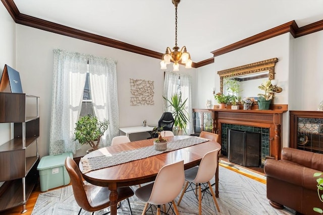 dining area featuring ornamental molding, plenty of natural light, a tile fireplace, and light wood-style flooring