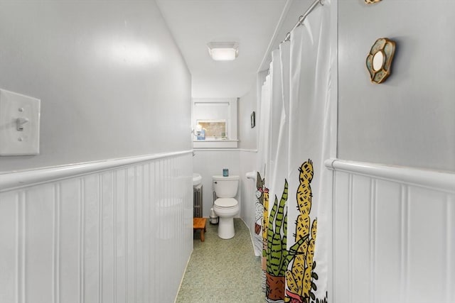 bathroom with toilet and a wainscoted wall