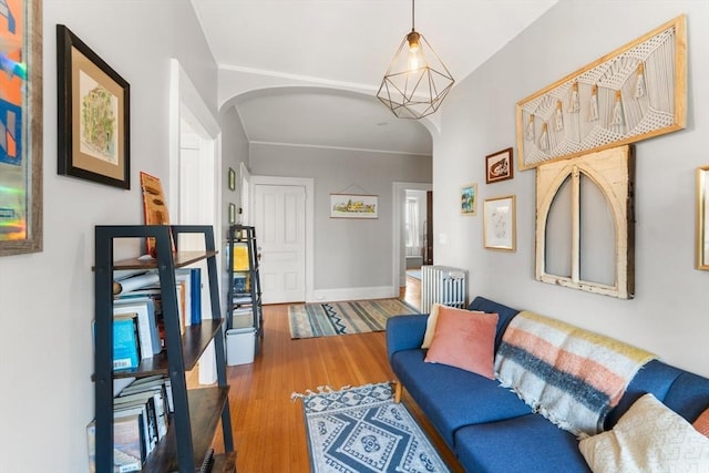 living area featuring baseboards, arched walkways, and wood finished floors