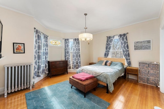 bedroom with radiator, multiple windows, and wood finished floors