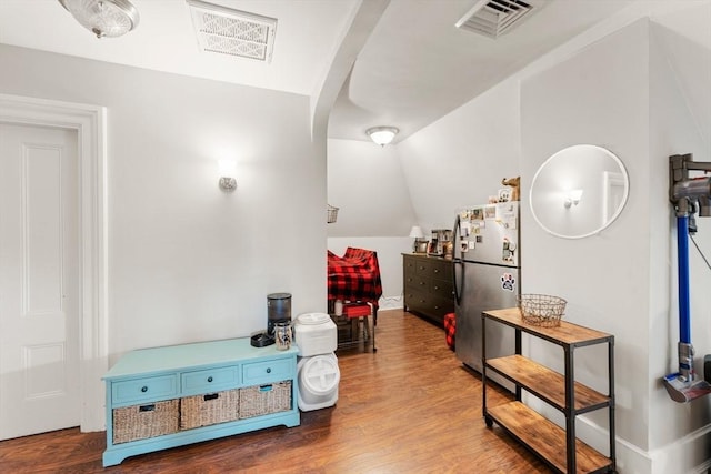 interior space with lofted ceiling, visible vents, and wood finished floors