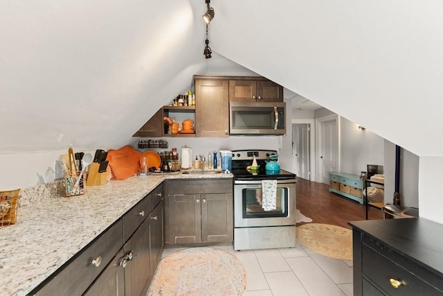 kitchen featuring lofted ceiling, stainless steel appliances, light stone counters, and open shelves