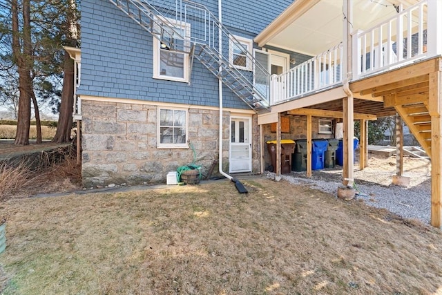 back of house featuring stone siding and a wooden deck