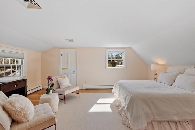 bedroom with a baseboard heating unit, lofted ceiling, wood finished floors, and visible vents