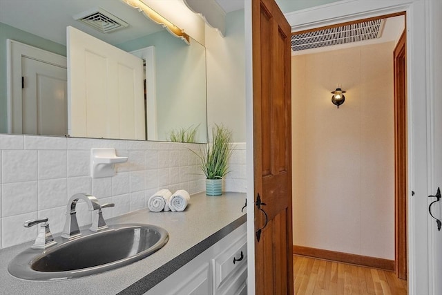 bathroom with visible vents, tasteful backsplash, and wood finished floors