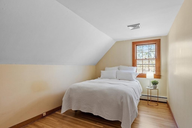 bedroom with visible vents, baseboards, lofted ceiling, baseboard heating, and light wood-style flooring