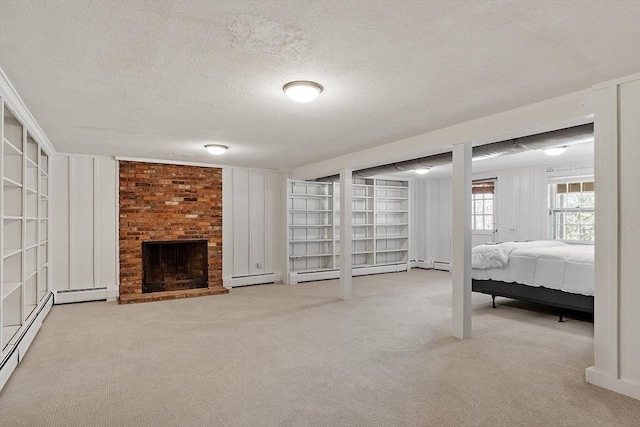 below grade area with a brick fireplace, carpet, a baseboard radiator, and a textured ceiling