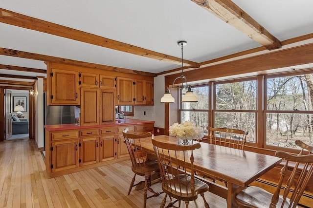 dining room featuring beam ceiling and light wood-style floors