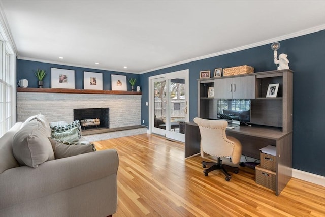 home office with light wood-style floors, a fireplace, crown molding, and baseboards