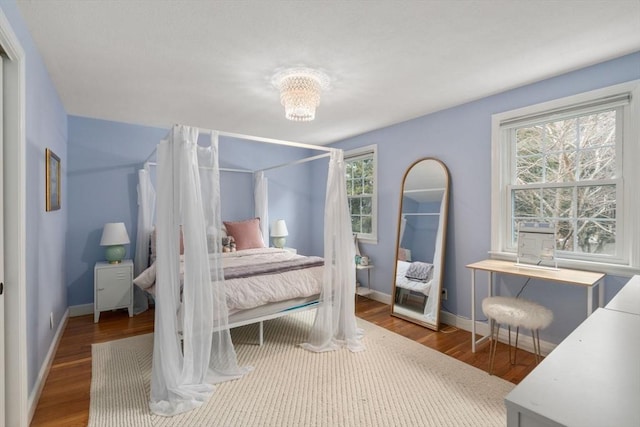 bedroom featuring a notable chandelier, baseboards, and wood finished floors