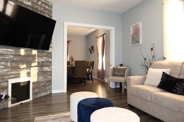 living room featuring dark hardwood / wood-style flooring and a stone fireplace