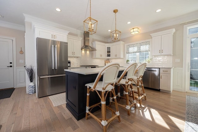 kitchen featuring appliances with stainless steel finishes, light wood-type flooring, wall chimney exhaust hood, and a healthy amount of sunlight