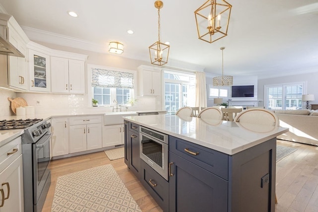 kitchen with white cabinets, appliances with stainless steel finishes, and decorative light fixtures