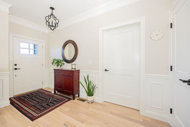 foyer featuring crown molding, a chandelier, and light hardwood / wood-style floors