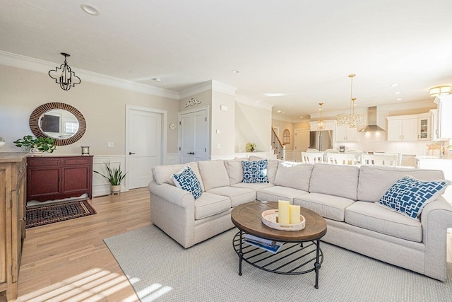 living room featuring crown molding, a chandelier, and light hardwood / wood-style flooring