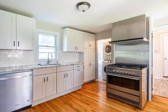 243 Bridge St, Northampton, MA 01060 - kitchen featuring appliances with stainless steel finishes, stacked washer and clothes dryer, a sink, and light wood-style floors