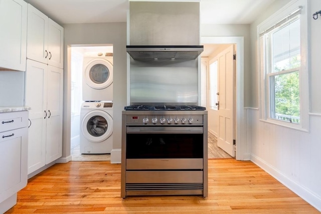 243 Bridge St, Northampton, MA 01060 - kitchen with stacked washing machine and dryer, high end stove, light wood finished floors, white cabinets, and light countertops