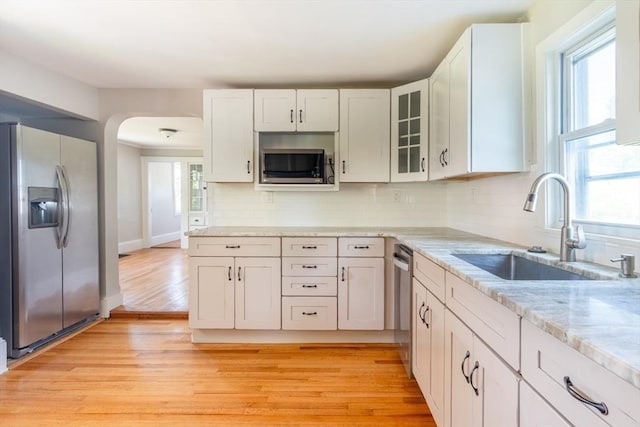 243 Bridge St, Northampton, MA 01060 - kitchen with appliances with stainless steel finishes, a sink, arched walkways, backsplash, and light wood-style flooring