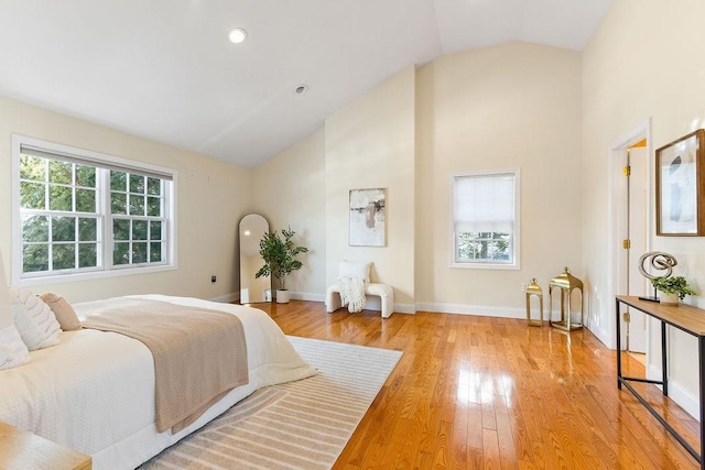 bedroom with multiple windows, high vaulted ceiling, and light hardwood / wood-style flooring