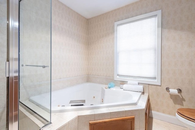 bathroom with tile patterned flooring, a relaxing tiled tub, and toilet