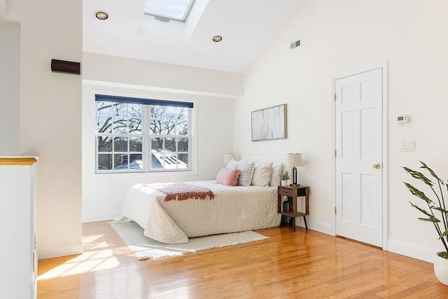 bedroom with a skylight, high vaulted ceiling, and light wood-type flooring