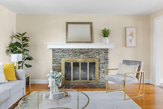 living room featuring a stone fireplace and hardwood / wood-style floors