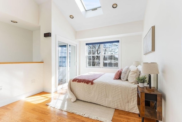 bedroom featuring lofted ceiling with skylight and light hardwood / wood-style floors