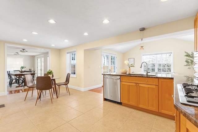 kitchen featuring vaulted ceiling, light tile patterned flooring, decorative light fixtures, sink, and stainless steel appliances